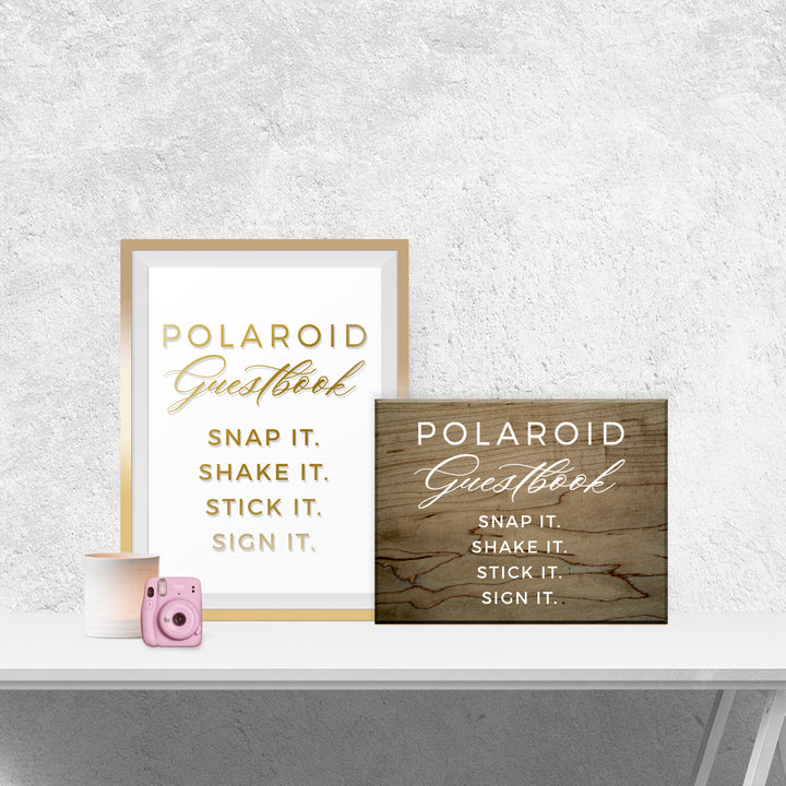 two framed signs on a white shelf, one with a pink camera and the other with a wooden sign.