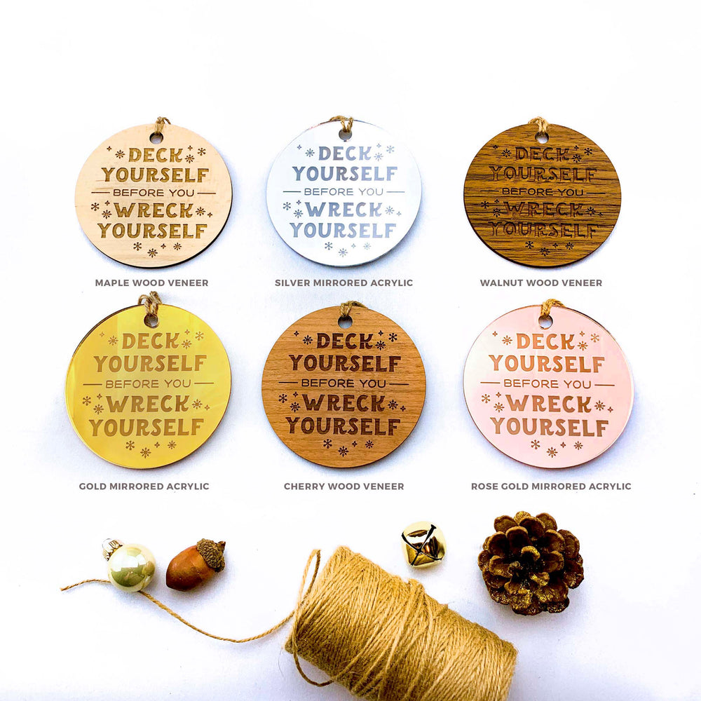 six circular ornaments with the same message "Deck Yourself Before You Wreck Yourself" printed on them, along with some pine cones and a spool of twine.