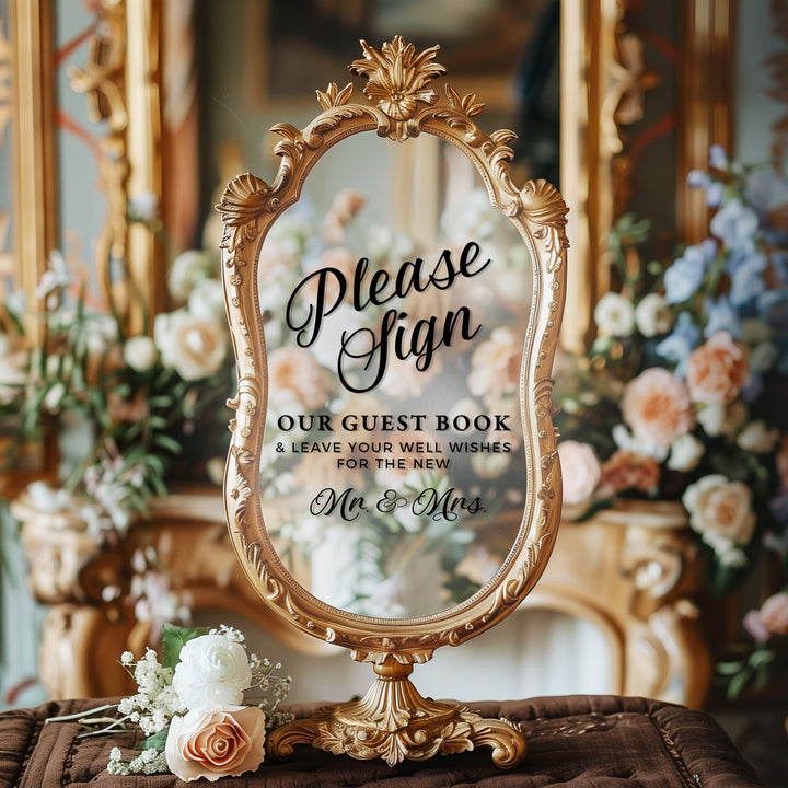 A decorative mirror with a sign in it, placed on a table with flowers.