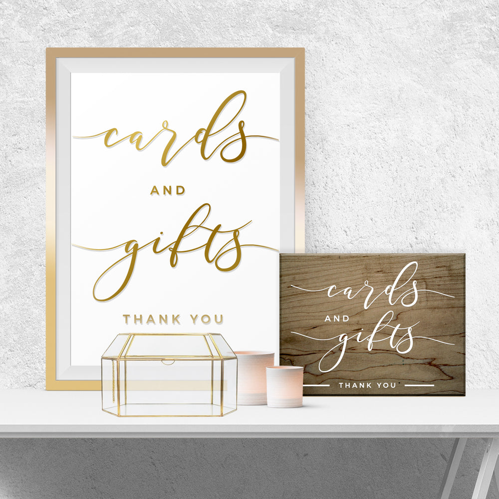 a framed sign that reads "cards and gifts" and a wooden sign that reads "cards and gifts" along with "Thank you" written below. There is also a small glass box and a candle on a white surface.
