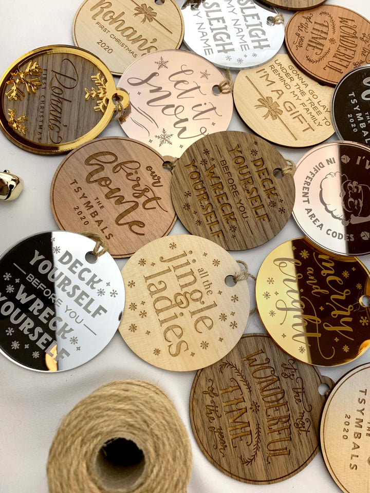 a collection of various wooden or metal tags with text and designs, including phrases like "Deck yourself before you wreck yourself", "Jingle ladies", and "Merry Christmas".