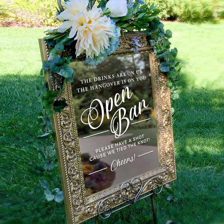a sign with a floral design and text, placed in a grassy area.