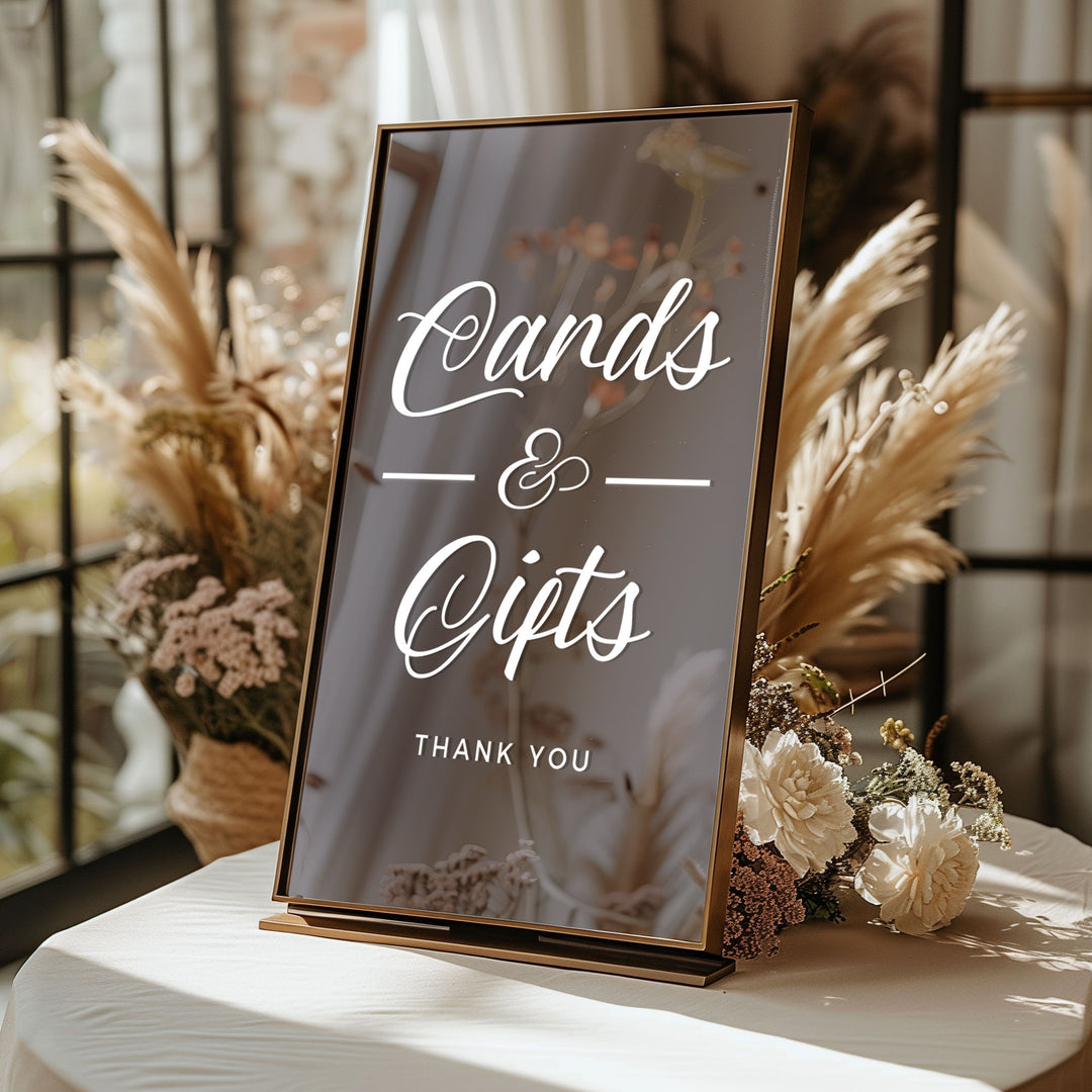 A sign that reads "Cards & Gifts" with a "Thank You" message, placed on a table with flowers and pom poms.