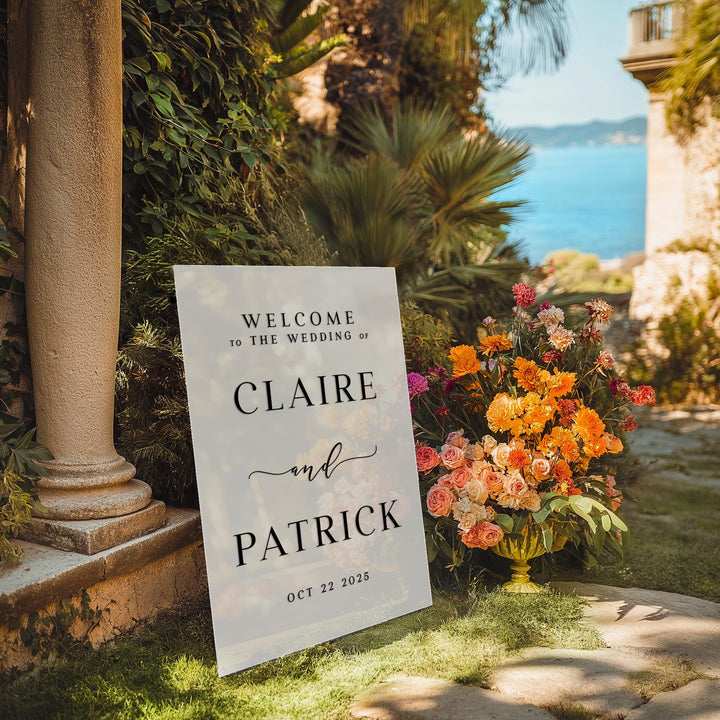 a welcome sign sitting in the grass next to a vase of flowers