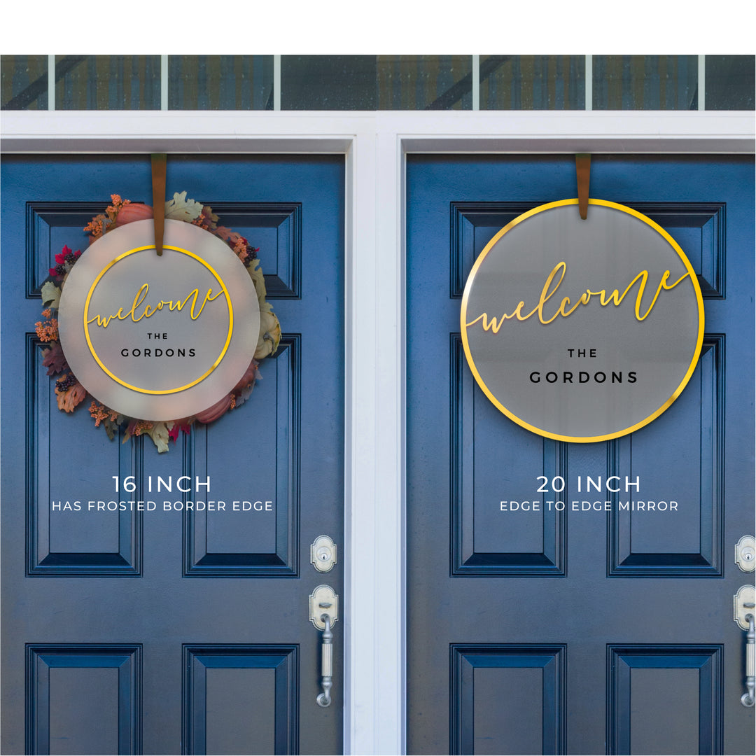 two blue doors with a welcome sign hanging on them. The sign is a circular design with the word "welcome" written in a decorative font. The sign is hanging at a height of 16 inches and has a frosted border edge of 20 inches.