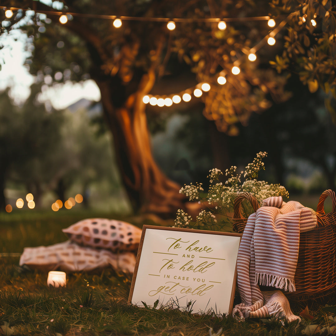 a serene outdoor setting with a wooden tree trunk, a wicker basket, and a sign that reads "To have and to hold in case you get cold". The scene is illuminated by string lights and has a warm, inviting atmosphere.
