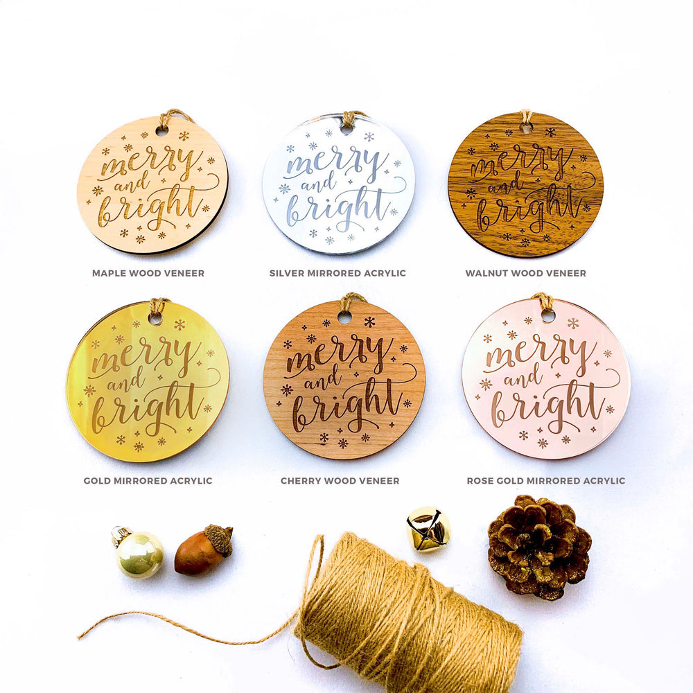 a collection of six round wooden tags with the text "mercy and brightness" written on them, along with various materials such as gold, silver, and wood veneers, as well as some ornaments and a spool of twine.