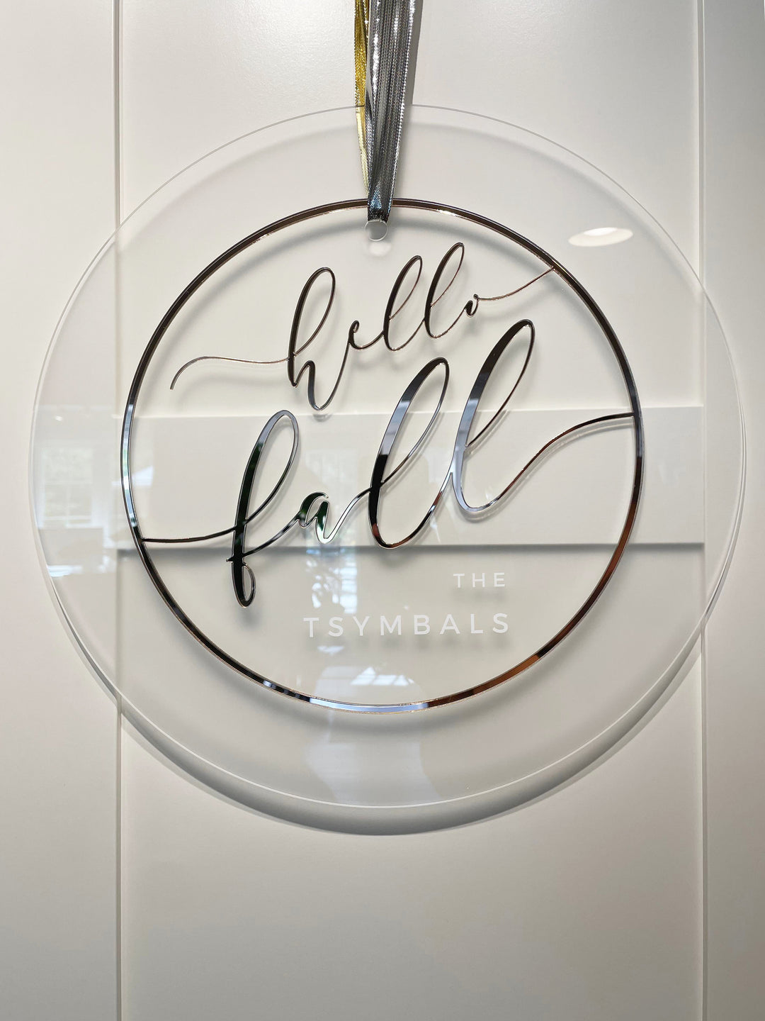 A clear glass sign with the text "Hello fall" written in a cursive font.
