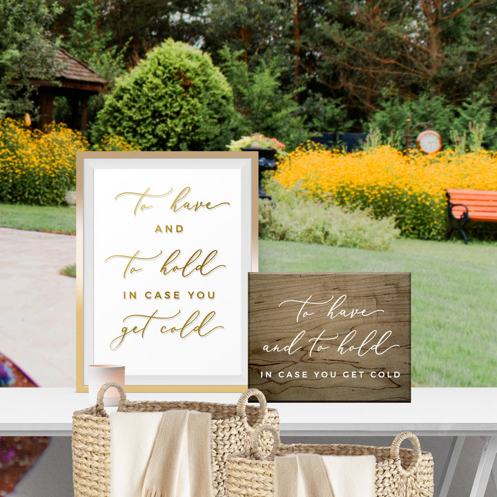 a sign with a message about staying warm, and a basket with a similar message, placed in a garden setting with yellow flowers and a bench.